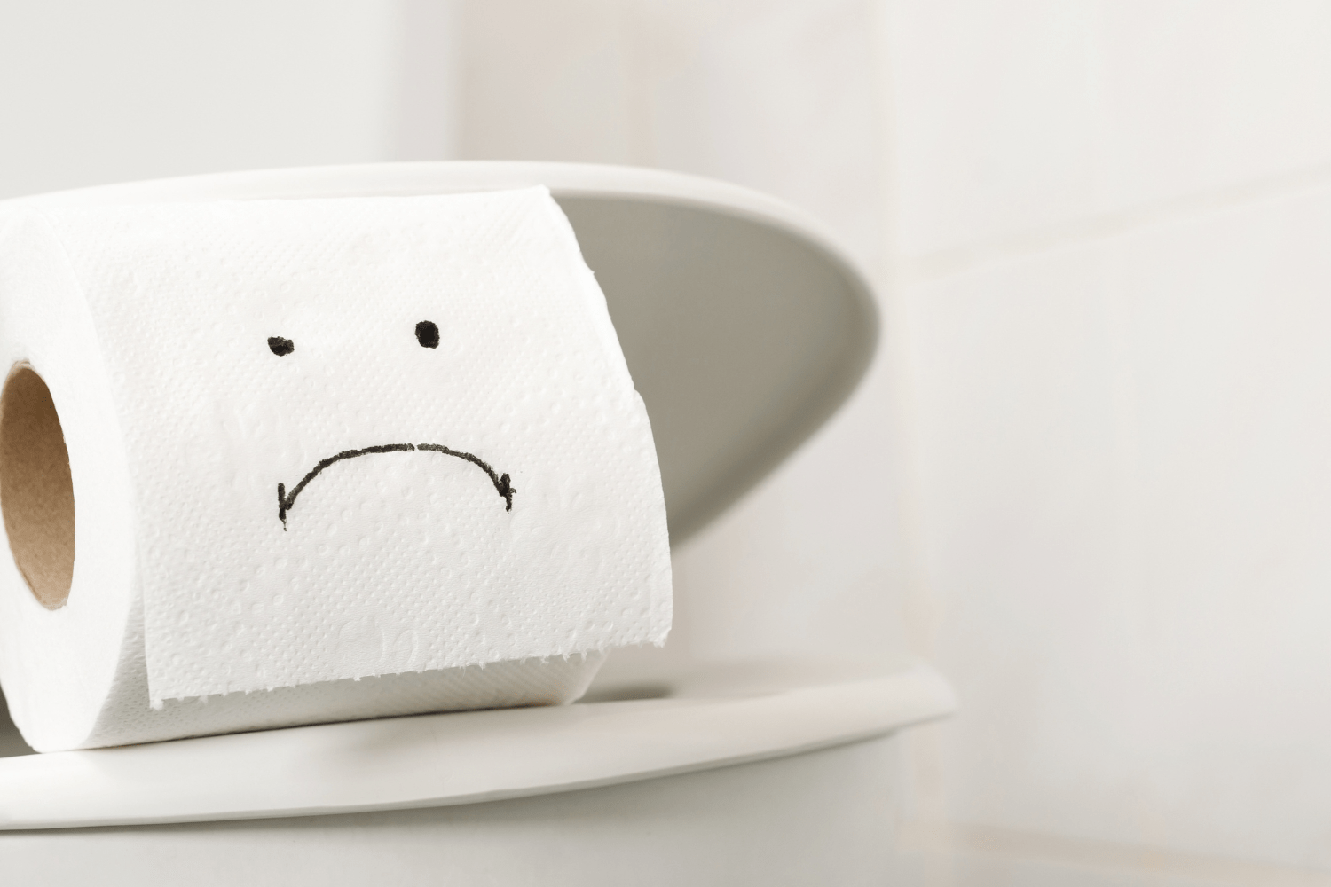 wc-paperi rulla wc-pöntön kannella - johon on piirretty surullinen naama