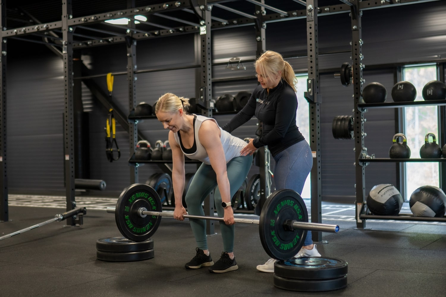 personal trainer ohjaa kuntosalilla asiakasta