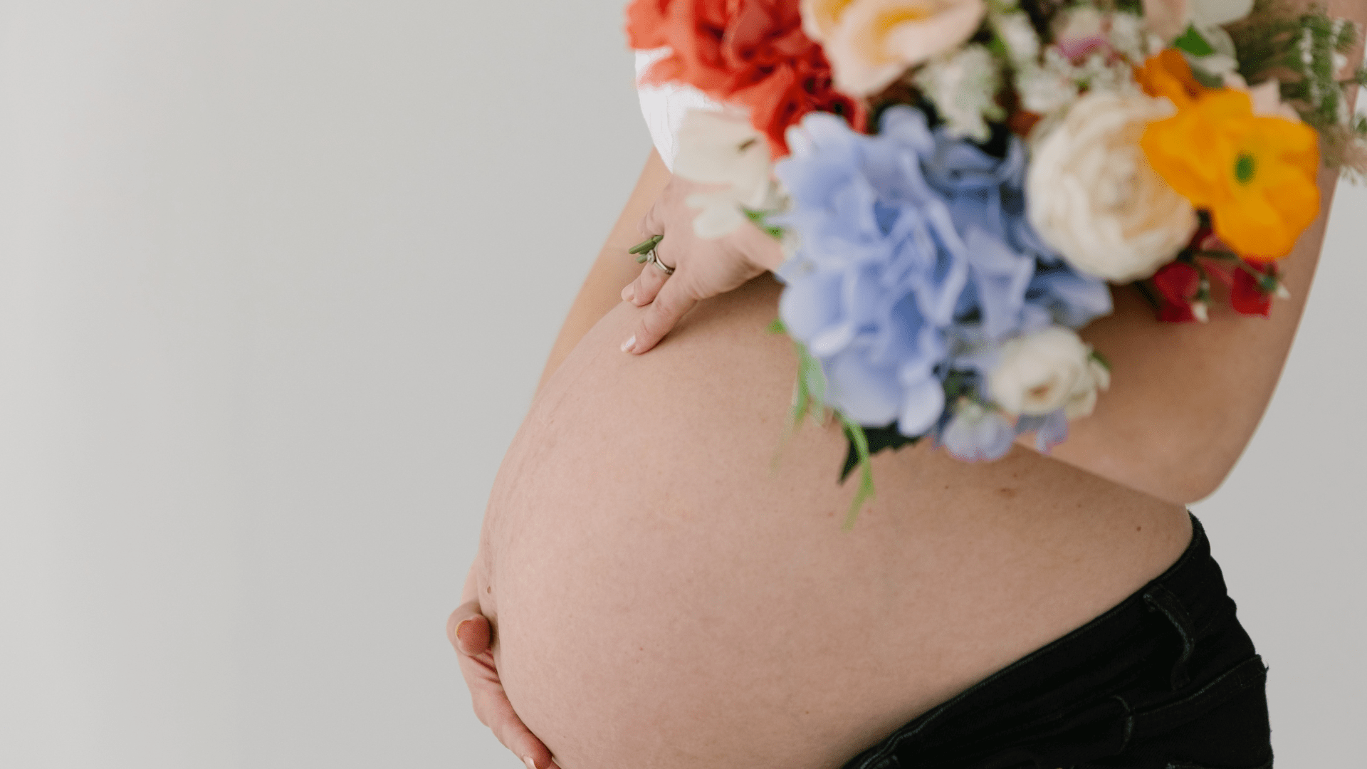 9Months-paketti raskaana oleville, kuvassa nainen pitelee raskausvatsaa ja toisella kädellä kukkia.
